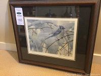 Full view of framed print leaning against wall on carpet