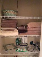 Stack of towels on wire shelving with showerhead and bath accessories