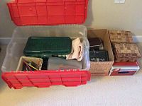 Wide shot of large plastic container and two smaller boxes containing art supplies, brushes and paint bottles.