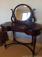 Front view of the wooden dressing table with round beveled mirror.