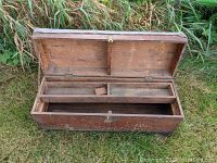 Closed wooden tool chest with hinged lid open, showing interior compartments and latch on front
