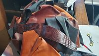 Top view of a large bag of leather scraps showing brown, black, and croc-textured pieces