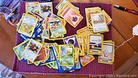 Pile of assorted Pokemon trading cards spread out on a surface, showing multiple characters and energy cards.