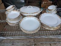 Wide view showing stacks of dinner plates, salad plates, bowls, cups and saucers, and a covered serving dish with matching Noritake Cruzon pattern.