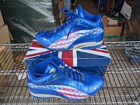 Side and bottom view of men's blue Avia sneakers with American flag patterns on the sides, placed on a box with a Union Jack design.