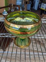 Angled side view of the green Depression glass candy dish showing gold bands around the bowl and foot.
