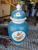 Chinese blue ginger jar with lid, detailed gold floral and vine patterns, white oval floral medallions, and gold accents
