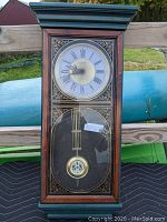 Full view of Verichron quartz hanging wall clock showing wooden case, divided glass front with clock face and pendulum.