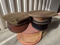 Two WWII US Army dress uniform hats side by side, showing differences in brim and band color.