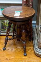 Front view of the round mahogany piano stool showing the turned legs and claw ball feet.