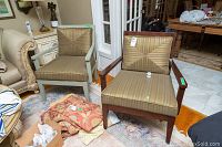 Pair of upholstered armchairs side by side, one in original dark brown finish, one repainted pale green with nicks and wear visible around arms and legs. Cushions striped in brown and beige.