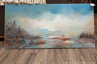 Full front view of the rectangular landscape oil painting with soft blue sky, trees, water and horizon.