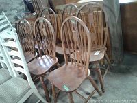 Six wooden dining chairs grouped together showing full view of chair design and finish.