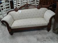 Full front view of the antique settee showing overall structure, upholstery, and carvings.