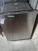 Front view of KitchenAid dishwasher showing stainless steel door with dimensions label (24x25x33 inches) and some surface marks.