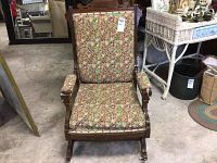 Front view of the rocking chair showing floral upholstery and carved wooden frame