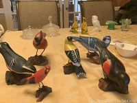 Full view of all six wood bird statues on table, showing size range and variety of birds.