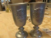 Pair of pewter beakers on table showing front Masquers Club emblem.