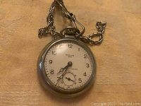 Front view of Westclox Dax pocket watch showing dial with Arabic numerals, sub-second dial, and attached metal chain.