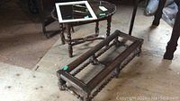 Antique wooden coffee table with glass top and white framed mirror on top, oak table frame in front on wood floor.
