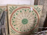 Full front view of one painted tin ceiling tile leaning against wall