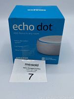 Front view of the blue box packaging of the Amazon Echo Dot, showing branding and product image.