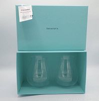 Two clear glass drinking glasses displayed inside a Tiffany & Co. light blue box with logo on lid, viewed from top.