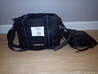 Black Olympus branded soft carry bag and Olympus Movie 8 VX-82 8mm movie camera side by side on wooden floor.