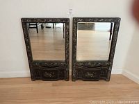 Pair of antique oriental vertical mirrors with dark hand-painted wooden frames and small drawers at bottom.