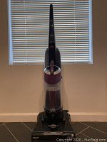 Full front view of the Bissell upright vacuum cleaner, showing the transparent dust container and handle.