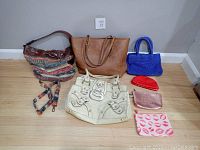 The entire lot laid out on the floor, showing all 4 purses and 3 makeup bags in various colors and styles