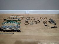 Wide view of costume jewelry including necklaces, bracelets, and earrings laid out on wooden floor