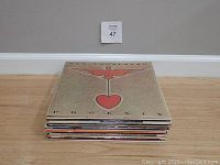 Stack of vinyl records on floor with Thin Lizzy Black Rose album on top.