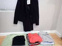 Overall lot on floor and black blazer with slacks hanging on wall