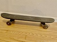 Side view of skateboard deck showing wear on grip tape and wheels