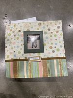 Scrapbook album cover with polka dot and striped patterned paper, photo frame with image, and decorative label.