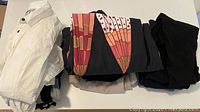 Stack of folded business professional women's clothing including a white blouse and colorful patterned tops.