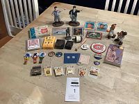 Wide overhead view of all items arranged on a table including cards, pins, figurines, whistles, woodblocks, Pewter figure, card games, and patches