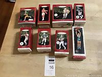Front view of all 8 boxed Hallmark sports collector ornaments arranged on table including Joe Montana, Muhammad Ali, Mario Lemieux, Cal Ripken Jr., Dan Marino, Joe Namath, Larry Bird, and an unidentified basketball player.