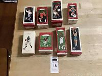 Boxed Hallmark Collectors Series sports ornaments with images of athletes on boxes, arranged on floor.