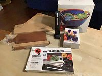 Assortment of kitchenware including boxes and items arranged on floor, showing bread boards, salad bowl, cruet set, cutlery box