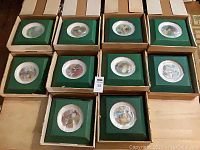 Overview of all 10 Carol Lawson collector plates in original boxes. Plates appear wrapped and include COAs. Boxes and wrapping materials show some wear.