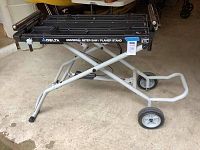 Side view of folding metal stand with two wheels and adjustable supports