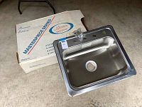 Photo of stainless steel sink with original box showing Masterpiece Premium Mirror Deck series labeling.