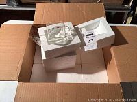 Open box containing multiple white styrofoam blocks with a Maxwell House cappuccino glass on top showing brand graphics.