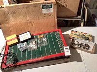 Overall view of the Tudor electric football game, player pieces in bags, and box of metal toy soldiers on table with original packaging