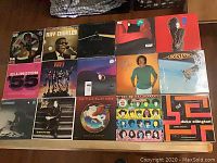 Overview of all 15 vinyl record sleeves laid out showing various album covers including Jackson 5, Kiss, Duke Ellington, Billy Joel, Boston, Ray Charles among others.