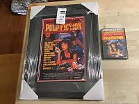 Wrapped framed poster and sealed DVD case side by side