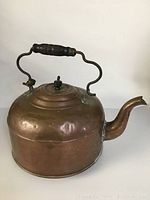 Side view of vintage copper kettle showing wooden handle and spout