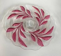 Top view of clear glass pedestal dish showing cranberry red leaf design and scalloped edges.